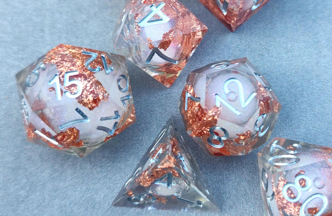 a piece of modern blackwork embroidery done in green thread sitting behind some ferns